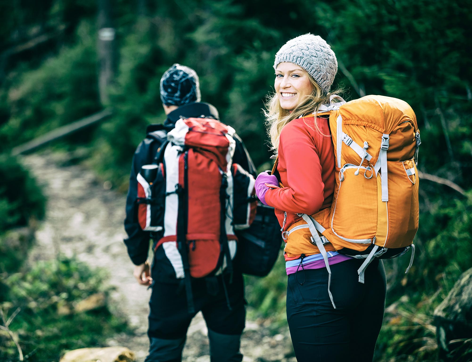 A woman smiles to show her healthy teeth during a hike Roxborough, CO.